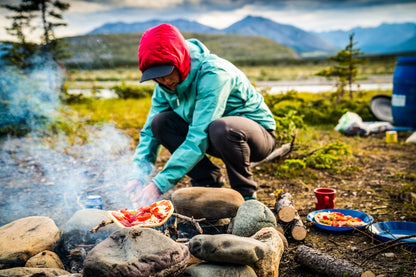 Our guide expertly cooking over the campfire, preparing a delicious meal after an unforgettable day of hiking in the Yukon. The warm glow of the fire and the aroma of fresh camp-cooked food complete the wilderness experience.